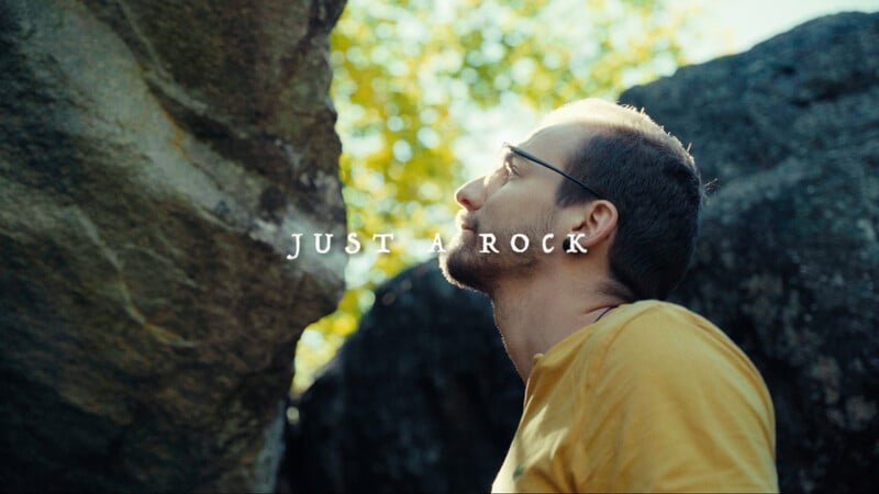 Promotional image for JUST A ROCK showing Emanuele Ticozzi between two boulders with the title centred